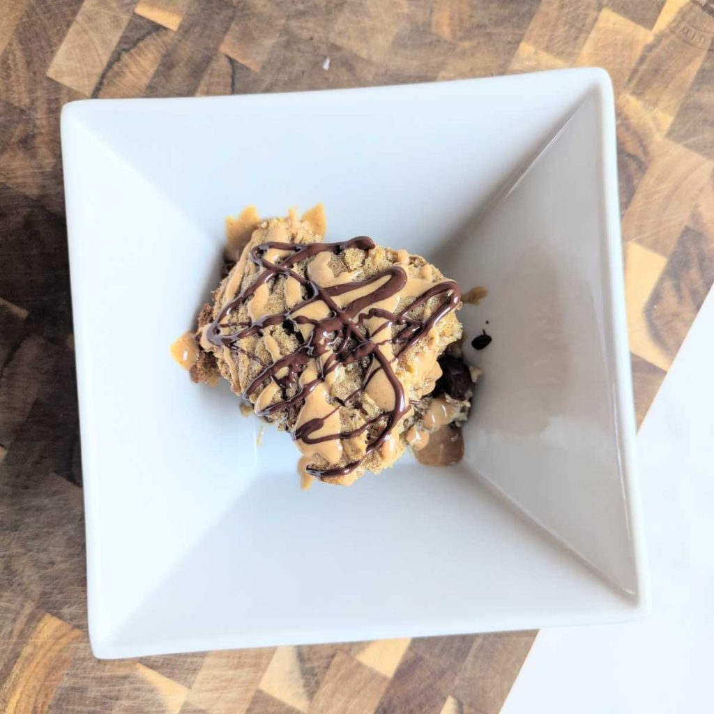 baked protein oats in bowl with peanut butter and chocolate drizzle