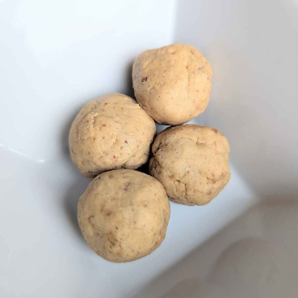 3 Chickpea protein balls stacked up in a square white bowl