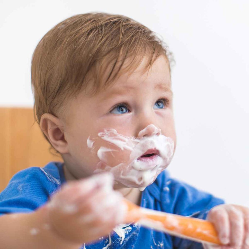 baby eating yogurt with spoon