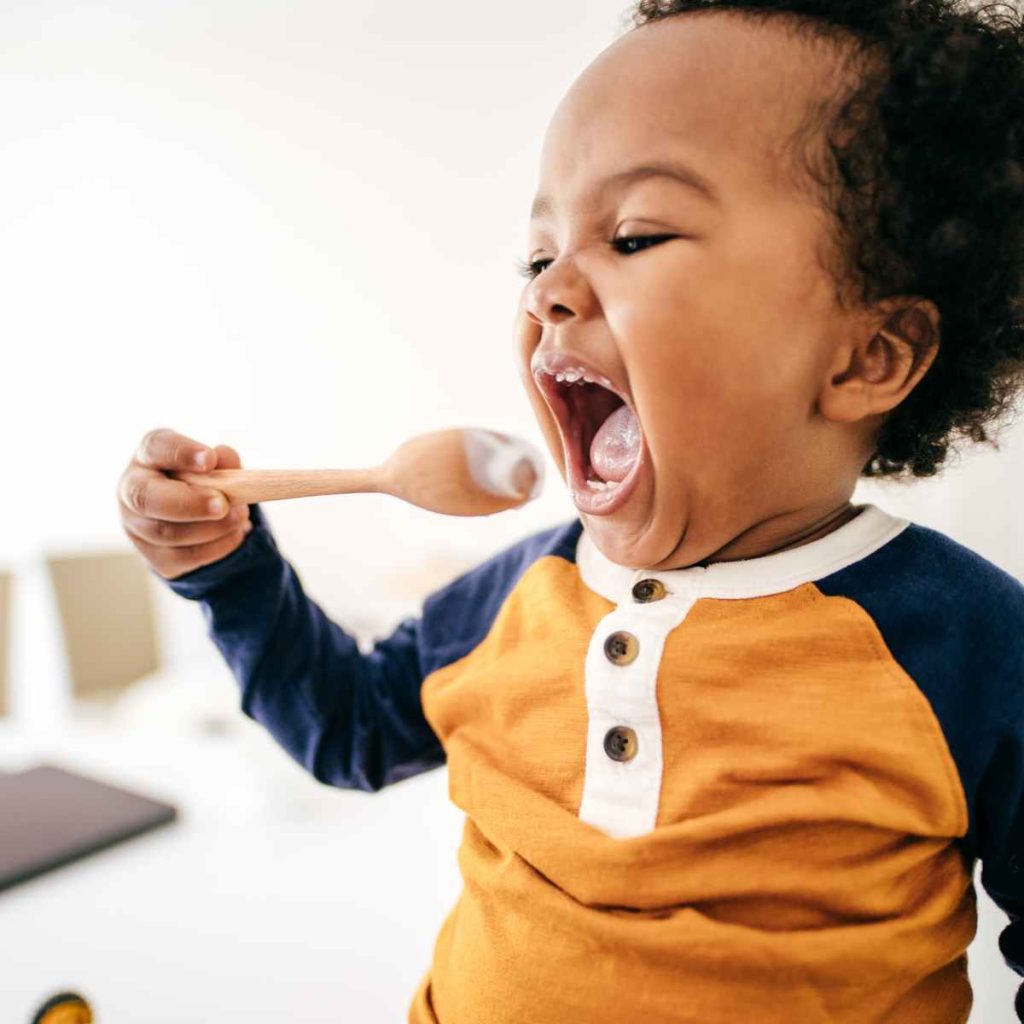 baby eating yogurt with spoon