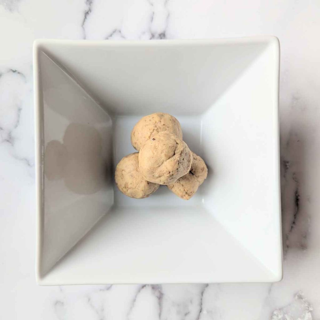 3 Chickpea protein balls stacked up in a square white bowl